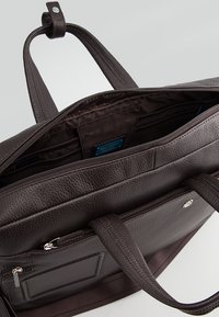 Borsa per laptop in pelle marrone con finitura testurizzata, manici doppi, più tasche interne e chiusura con zip per una facile sicurezza.