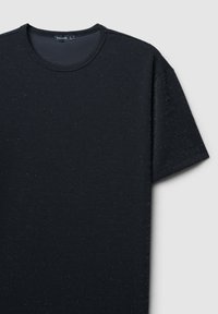 T-shirt nera realizzata in tessuto testurizzato con leggere punte di argento, scollo rotondo, maniche corte e vestibilità rilassata. Etichetta del marchio visibile all'interno.