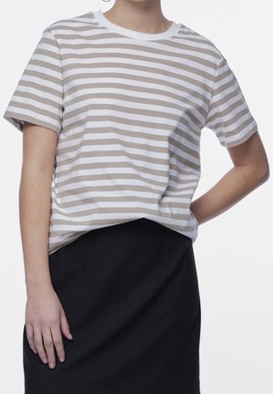 Lekka bawełniana koszulka w poziome beżowo-białe paski, z okrągłym dekoltem i krótkimi rękawami, zestawiona z czarną spódnicą.