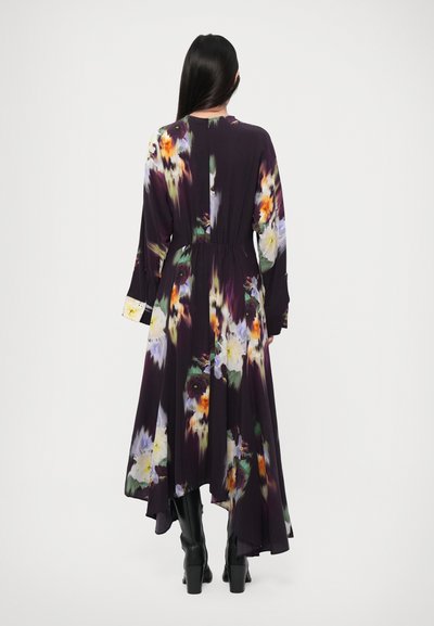 Long, flowing dress in dark purple fabric with a floral print in yellow, orange, and green. Features long sleeves and a gathered waist.
