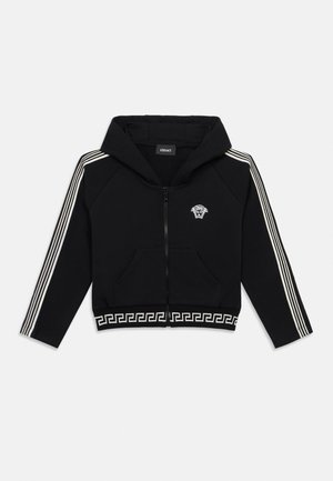 Svart hettegenser med glidelås, hvitt gresk nøkkelmønster på kanten, hvite striper på ermene og liten Medusa-logo på venstre bryst.