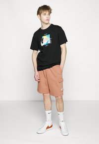 Nike Sportswear CLUB CARGO - Calças de fato de treino - mineral clay/white