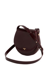 Burgundy leather crossbody bag with a curved shape, gold bee accent, adjustable strap, and smooth texture. Closure with a flap design.