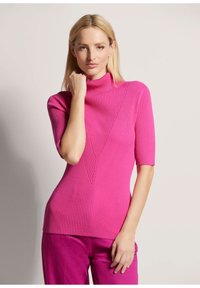 Eng anliegendes, geripptes Rollkragenoberteil in lebhaftem Pink, mit V-förmigem Design auf der Vorderseite und kurzen Ärmeln. Weiche Textur, vielseitig kombinierbar mit verschiedenen Outfits.