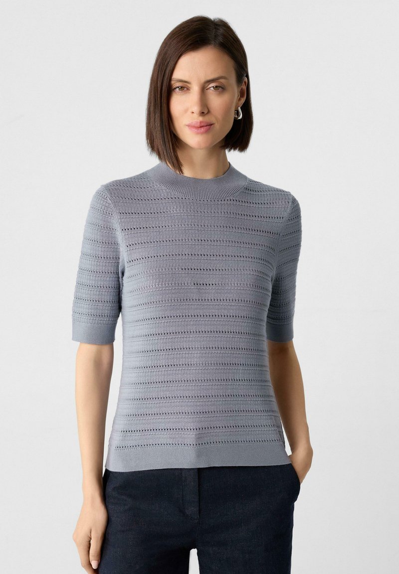 Hellgrauer Strickpullover mit kurzen Ärmeln, ausgestattet mit einem strukturierten Streifendesign und einem runden Halsausschnitt. Aus weichem und atmungsaktivem Material.