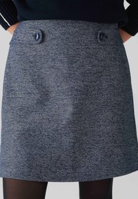 Donkerblauwe rok met een gestructureerde weef, voorzien van twee decoratieve knopen bij de taille en een recht gesneden ontwerp. Het materiaal lijkt stevig.