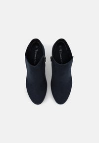 Botas de tobillo azul marino hechas de suave gamuza, con una cremallera en el lateral y un diseño de punta afinada. Talla 37 marcada visiblemente en el interior.
