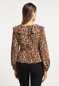 Brun og sort leopardprint bluse med rynket krave, lange ærmer og tætsiddende design, lavet af blødt stof.