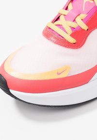 Lightweight athletic shoe in pink and orange hues. Features breathable mesh upper, textured surface, contrasting laces, and logo detail.