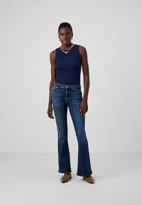 Top sem mangas azul-marinho combinado com jeans azul-escuro com bainha flare. O tecido é macio e os jeans apresentam um design clássico de cinco bolsos.