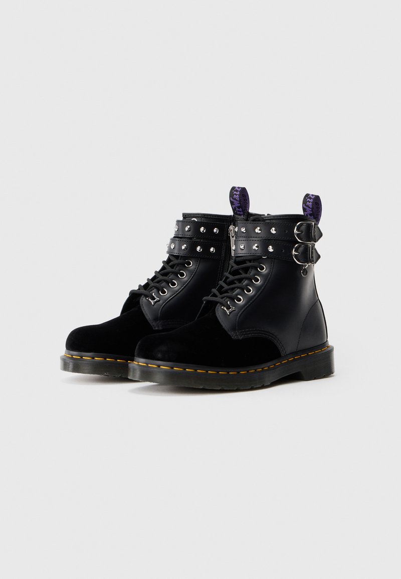 Black ankle boots featuring a combination of leather and velvet, silver studs along the cuff, lace-up front, and thick rubber sole with yellow stitching.