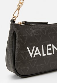 Borsa a tracolla nera in pelle sintetica testurizzata, con un logo bianco ben visibile, hardware dorato e un motivo trapuntato.