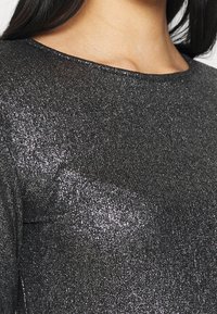 Black metallic top featuring a smooth, reflective texture with a rounded neckline and long sleeves. Shimmering fabric with fine details.