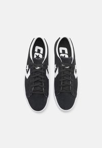 Schwarze Wildleder-Sneaker mit weißen Akzenten, featuring ein Sternenlogo, runde Zehen und schwarze Schnürsenkel. Gummisohle mit strukturiertem Grip.