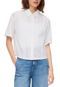 Witte korte mouwen overhemdd met een kraag, voorzien van oogjespatronen en een ontspannen pasvorm, gecombineerd met blauwe denim jeans.