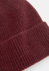 Burgundy neulepipo, jossa on ribbitekstuuri ja käännetty reunus. Valmistettu pehmeästä ja lämpimästä materiaalista, joka sopii kylmään säähän.