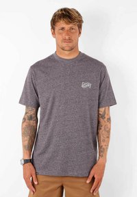 T-shirt gris en mélange avec des manches courtes, un col rond et un petit logo sur la poitrine. Le matériau semble doux avec une coupe décontractée.