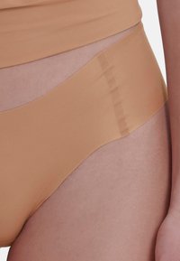 Naadloze huidkleurige slip met een zachte textuur en een soepele tailleband. Heeft een minimalistisch ontwerp en een aansluitende snit, geschikt voor dagelijks gebruik.
