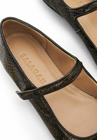Donkergroene en zwarte schoenen met slangenpatroon, met een matte afwerking, voorzien van een mary-jane band en een soepele beige voering.