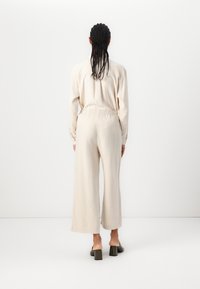 Beige leveled-hame jumpsuit nagireh, me vihelbeĩ yés tongo, gilate karé yúhya. Bakes sândă mankās ta yungīni tahi vāiīu.