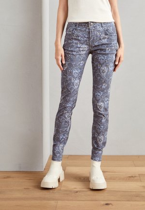 Modré džíny s paisley vzorem a slim fit, s pěti kapsami a zipovým zapínáním, doplněné robustními krémovými platformovými botami.