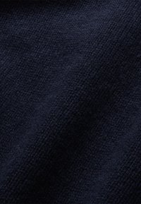 Sötétkék, texturált szövet, puha, domború mintázattal. Az anyag vastagnak és kényelmesnek tűnik, enyhén bolyhos felülettel.