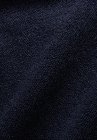 Marineblauwe textuurstof met een zacht, verheven patroon. Het materiaal lijkt dik en comfortabel, met een licht fuzzy oppervlak.