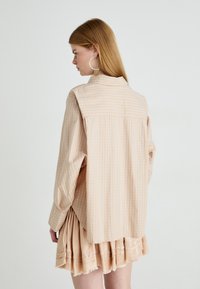 Licht geruite blouse met een ontspannen pasvorm, met lange mouwen en een afgeronde zoom, gecombineerd met een textuur met perzikkleurige plooien.