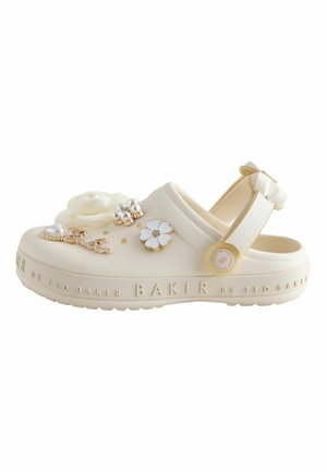 Cream-colored slip-on clog with floral and pearl charms, adjustable heel strap, and embossed brand name "BAKER" on the sole edge.
