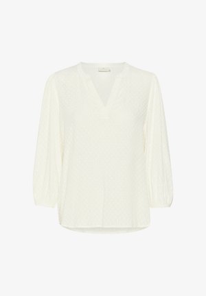 Balta garām piedurknēm blūze ar V-veida kakla izgriezumu, teksturētām punktiņām un saplacinātām piedurknēm. Izgatavota no viegla auduma un tai ir taisna apakšmala.