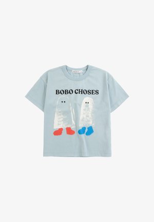 Lyseblå t-shirt med korte ærmer med teksten "BOBO CHOSES" og to abstrakte spøgelsesfigurer iført røde og blå sko foran.