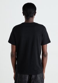 T-shirt en coton noir avec un col rond et des manches courtes, présentant un design uni et une coupe classique, vue de dos.