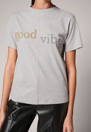T-shirt gris à manches courtes en coton, avec "good" en doré et "vibes" en argenté, col rond et coupe régulière.