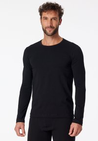 T-shirt a maniche lunghe nero realizzato in tessuto morbido, con scollatura rotonda e design aderente caratterizzato da una texture liscia.