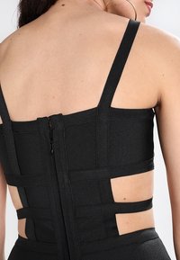 Svart, figurnära bodice med utskärningar, elastiskt material, tunna remmar och en mittdragkedja på baksidan. Texturerad design som förbättrar utseendet.