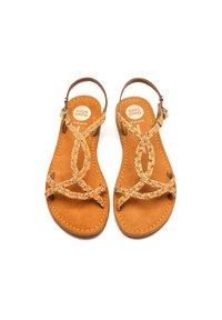 Sandali in pelle color nocciola con suola piatta, dotati di cinturini decorativi incrociati e dettagli floreali. Cinturino alla caviglia regolabile per una vestibilità sicura.