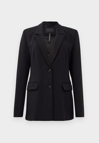 Blazer nero su misura con rever a taglio, due tasche frontali a filetto, due bottoni e una tasca sul petto a filetto, etichettato GUESS all'interno del colletto.
