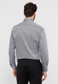 Camicia manica lunga con un motivo geometrico in navy e bianco, realizzata in tessuto intrecciato, con colletto standard e polsini abbottonati.