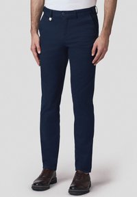 Granatowe chinosy wykonane z mieszanki bawełny, w wąskim kroju, z szlufkami na pasek, dwoma bocznymi kieszeniami oraz zamkiem błyskawicznym z zapięciem na guzik.