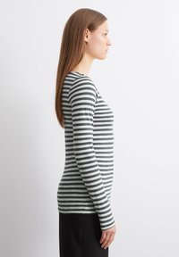 Pilkos ir baltos šypsenos juostinė marškinė su ilgomis rankovėmis. Slim fit, apvalus kaklo iškirpimas, minkšta medžiaga, su tolygiai išdėstytais horizontaliais džinsais.