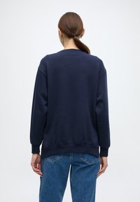 Μπλε σκούρο φούτερ με στρογγυλή λαιμόκοψη, ριμπ μανσέτες και ζώνη στη μέση. Κατασκευασμένο από απαλό ύφασμα, διαθέτει άνετη εφαρμογή και λεία υφή.