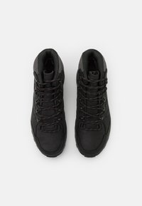 Schwarze Wanderschuhe mit einem hohen Design, aus strukturiertem Leder und synthetischem Material. Merkmale sind kontrastierende rote Schnürsenkel und Ösen.