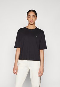 T-shirt cropped nera realizzata in cotone morbido con maniche corte. Presenta un piccolo logo triangolare sul petto sinistro. Texture liscia.