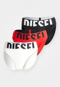 Drie paren korte onderbroeken: zwart, rood en wit. Elk heeft een brede elastische tailleband met het "DIESEL" logo in contrasterende kleuren. Gladde textuur.