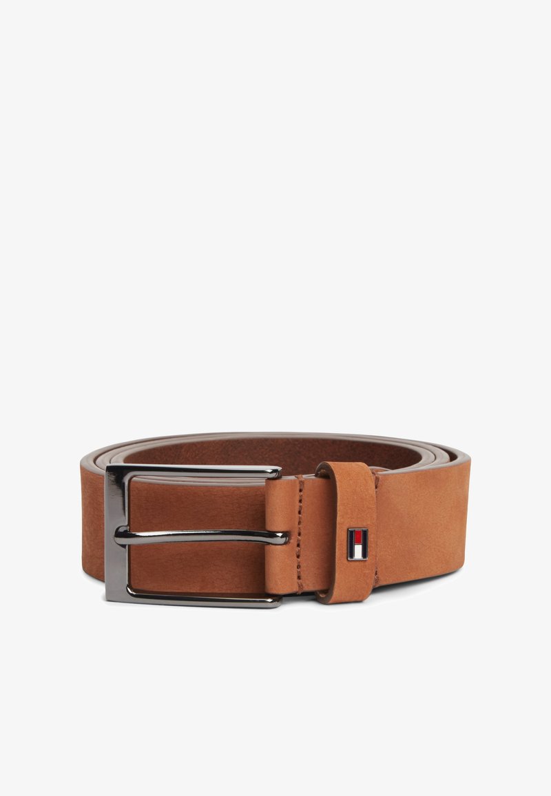 Καφέ δερμάτινη ζώνη με ασημένια ορθογώνια αγκράφα και μικρό κόκκινο, λευκό και μαύρο λογότυπο στη θηλιά της ζώνης, τυλιγμένη πάνω σε λευκό φόντο.