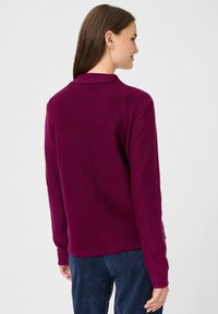 Long-sleeve, collar sweater in deep burgundy, made of textured knit. Features ribbed cuffs and hem, paired with dark corduroy pants.