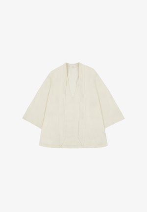 Top ligero de lino en color blanco roto. Presenta mangas anchas, un escote en V profundo y un diseño de frente abierto con costuras verticales. Textura suave.