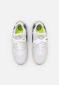 Vita och beige sneakers med ett rutmönster, en svart accentpanel, vita snören och ljusgröna innersulor med ett blommönster.