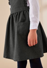 Tumehall kleit kogutud seeliku, küljetasku ja volangustega paeltega, koos valge pika varrukaga särgiga ja tumedate sukkpükstega.