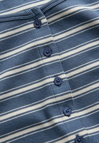Blue and white striped fabric with navy blue four-hole buttons sewn vertically down the center.